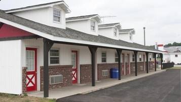 A row of single-story buildings with a covered walkway, brick walls, and red-framed windows.