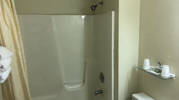 Ein Badezimmer mit Duschkabine, Toilette und Ablage für Tassen.