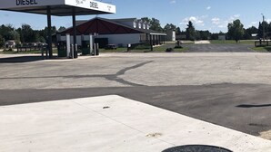 A gas station with a diesel pump, a covered waiting area, and a building with a red roof. - Quik Stop and Motel (Wausaukee)