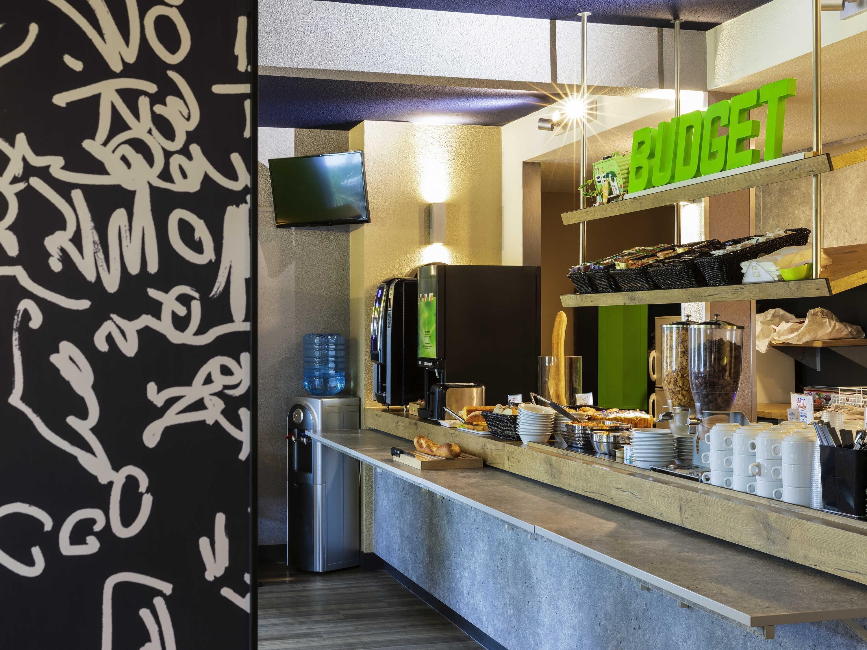 Een ontbijtbuffet met een koffieapparaat, waterkraan en diverse etenswaren.
