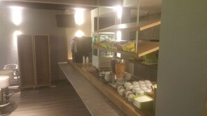 Un coin cuisine équipé d’un réfrigérateur, d’un four à micro-ondes et de diverses provisions rangées sur des étagères.