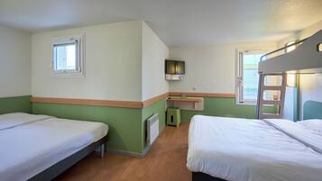 A room with two beds, a small desk, a TV, and a window.