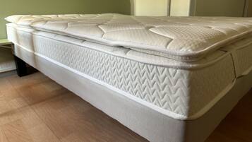 Un colchón en una habitación con cabecera verde y suelo de madera.