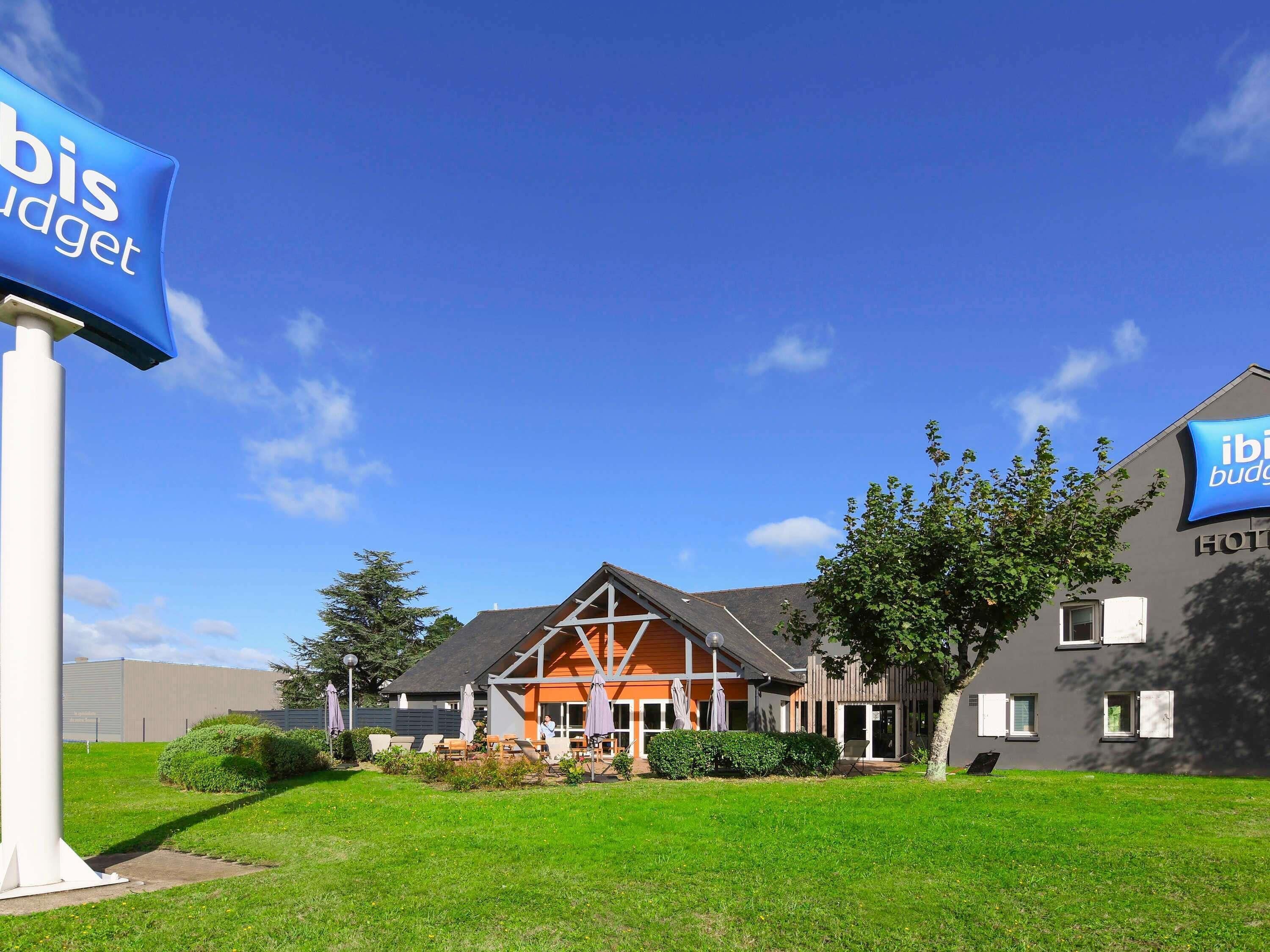 A hotel with a signboard, a well-maintained lawn, and a building with a distinct architectural style.