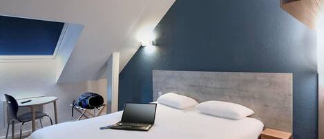 Una habitación de hotel moderna con una cama grande, un escritorio y una silla.