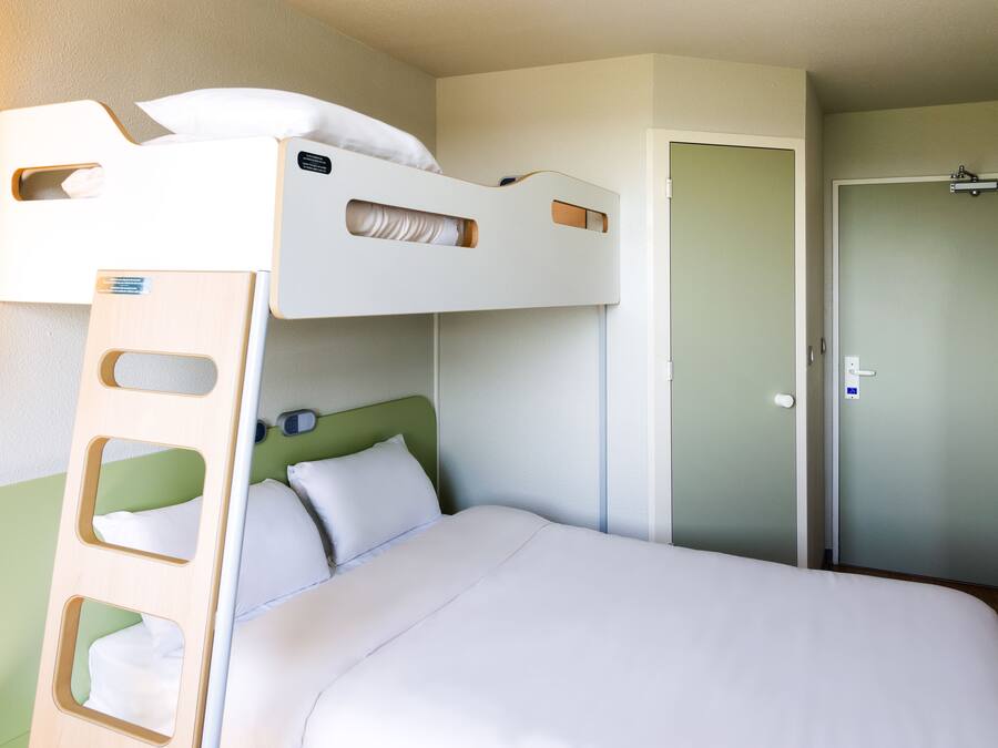 Una cama litera con escalera, una mesita de noche y una puerta en una habitación de hotel.