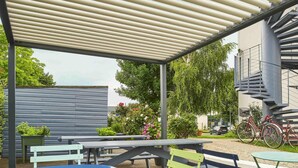 An outdoor patio with tables and chairs, a covered area, and a staircase. - ibis budget Santeny (Santeny)