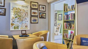 A library with leather chairs, a map, framed photos, and bookshelves. - ibis budget Santeny (Santeny)