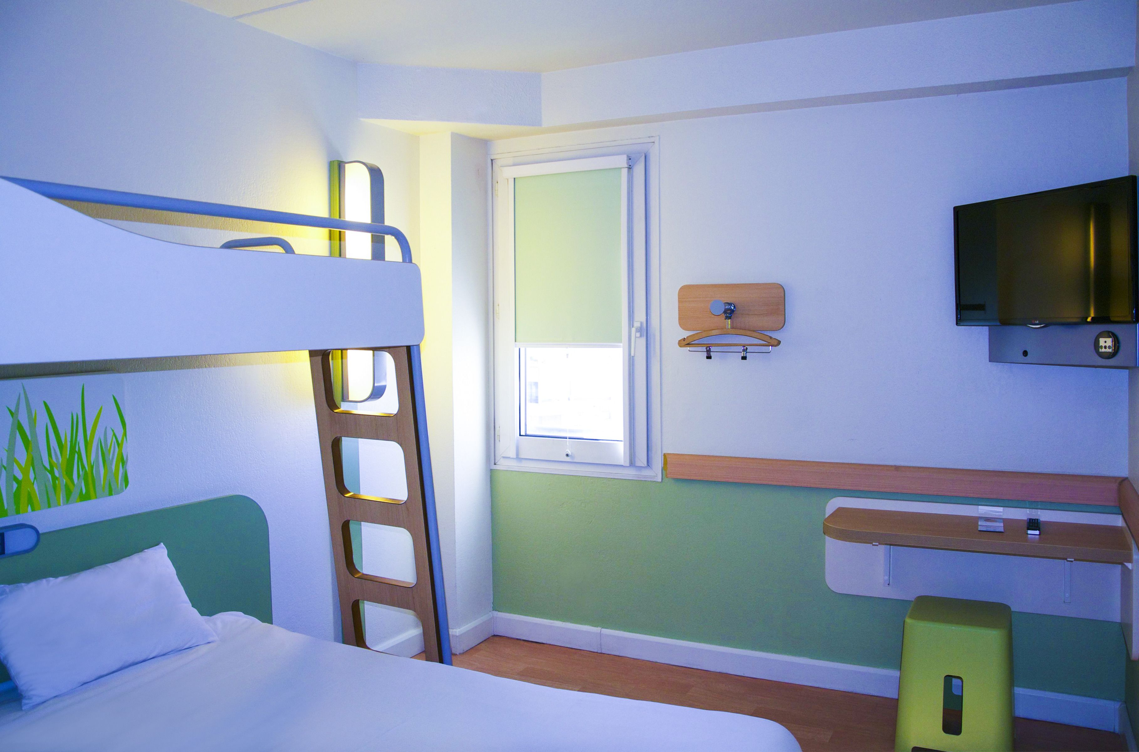 Une chambre avec des lits superposés, un bureau, une télévision et une fenêtre.