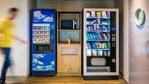 Een automaat met snacks en een magnetron erboven.