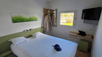Une chambre d’hôtel avec un lit, une télévision, une fenêtre donnant sur un paysage agréable et un porte-manteau.