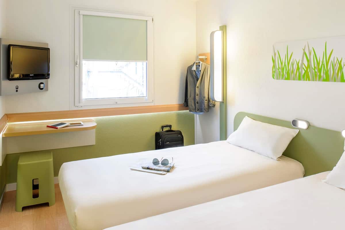 Une chambre d’hôtel avec un lit, un bureau, une télévision et une fenêtre.