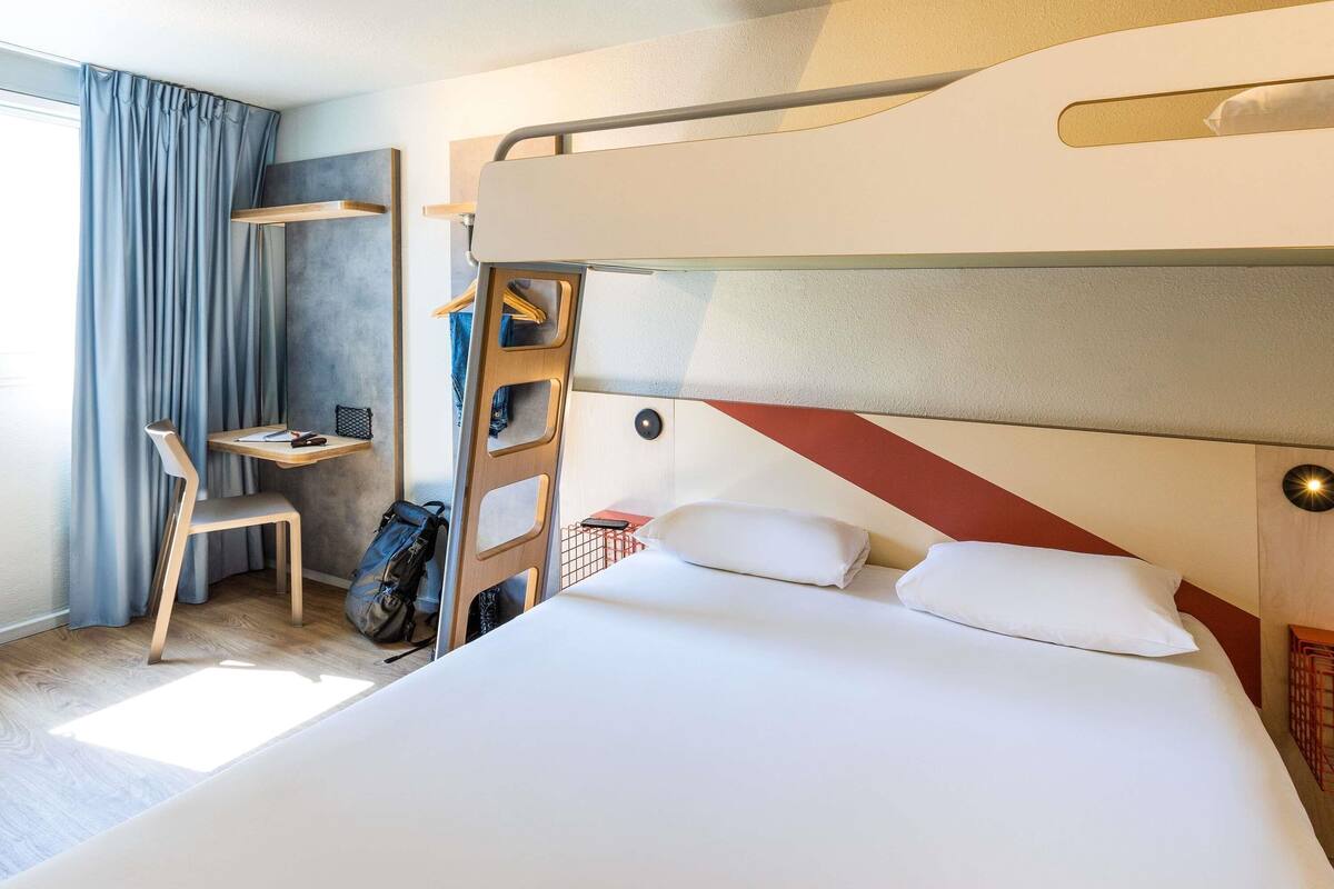 Quarto com beliche, escrivaninha, cadeira e cabideiro.