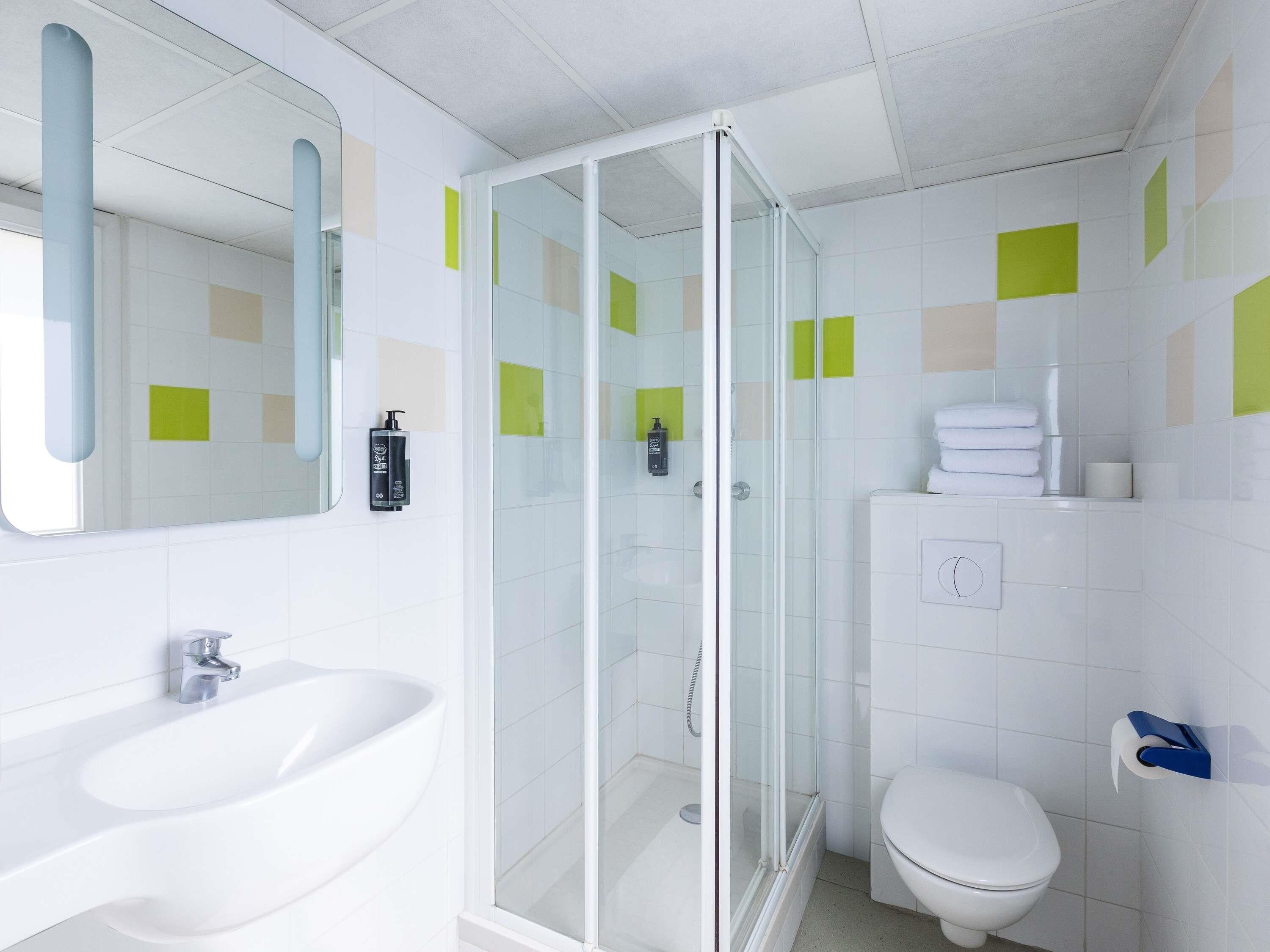 A modern bathroom with a glass-enclosed shower, a white sink, and a toilet.