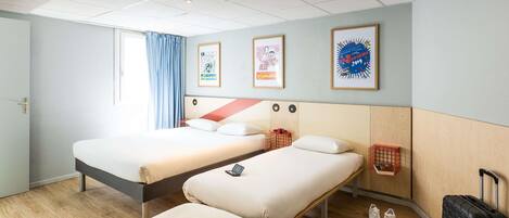 A hotel room with two beds, a desk, a chair, a suitcase, and a window with curtains.