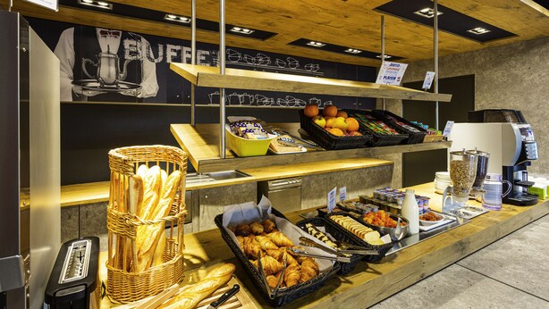 Zona de bufé con diferentes opciones de comida, como pan, frutas y bebidas.