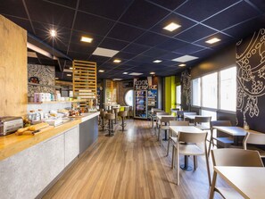 Interior moderno de una cafetería con mostrador, zona de estar y una máquina expendedora.