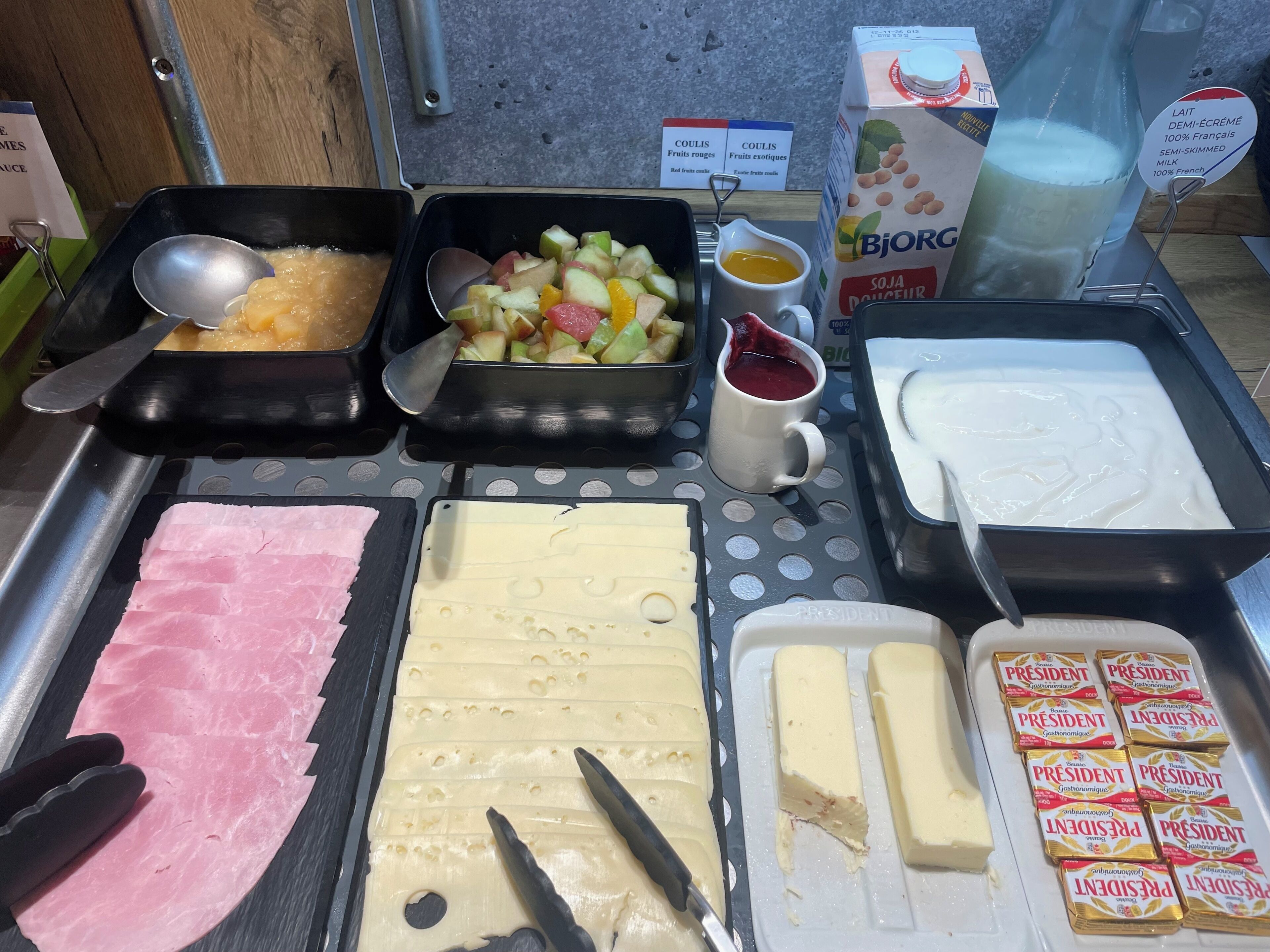 A buffet with various food items including fruits, meats, and dairy products.