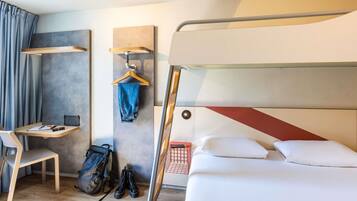 A modern hotel room with a bunk bed, a desk with a chair, a hanging coat rack, and a suitcase on the floor.