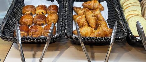 Three baskets of baked goods with tongs, placed on a counter.
