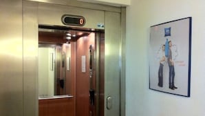 Un ascensor con una pantalla digital que muestra '0', revestimiento de madera y un cartel en la pared.