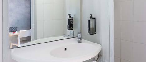 Un baño moderno con un lavamanos blanco, un espejo y un perchero para toallas.