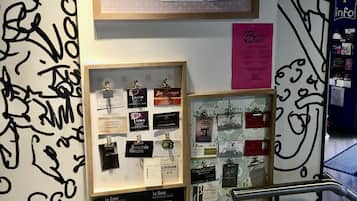 A wall with various framed items, including business cards, a sign with a 5% discount offer, and a section labeled "Bons Plans" with a blackboard.