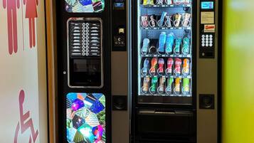 Two vending machines with various beverages and snacks, a payment keypad, and a wheelchair accessibility sign.