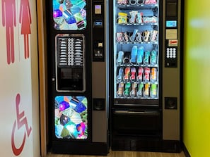 Two vending machines with various beverages and snacks, a payment keypad, and a wheelchair accessibility sign. - ibis budget Angoulême Centre (Angouleme)
