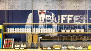 A buffet setup with various food items and utensils on display. - ibis budget Deauville (Saint-Arnoult)