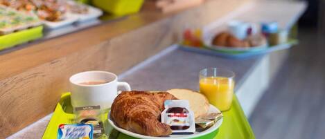 A breakfast buffet with croissants, juice, and a coffee cup on a tray.