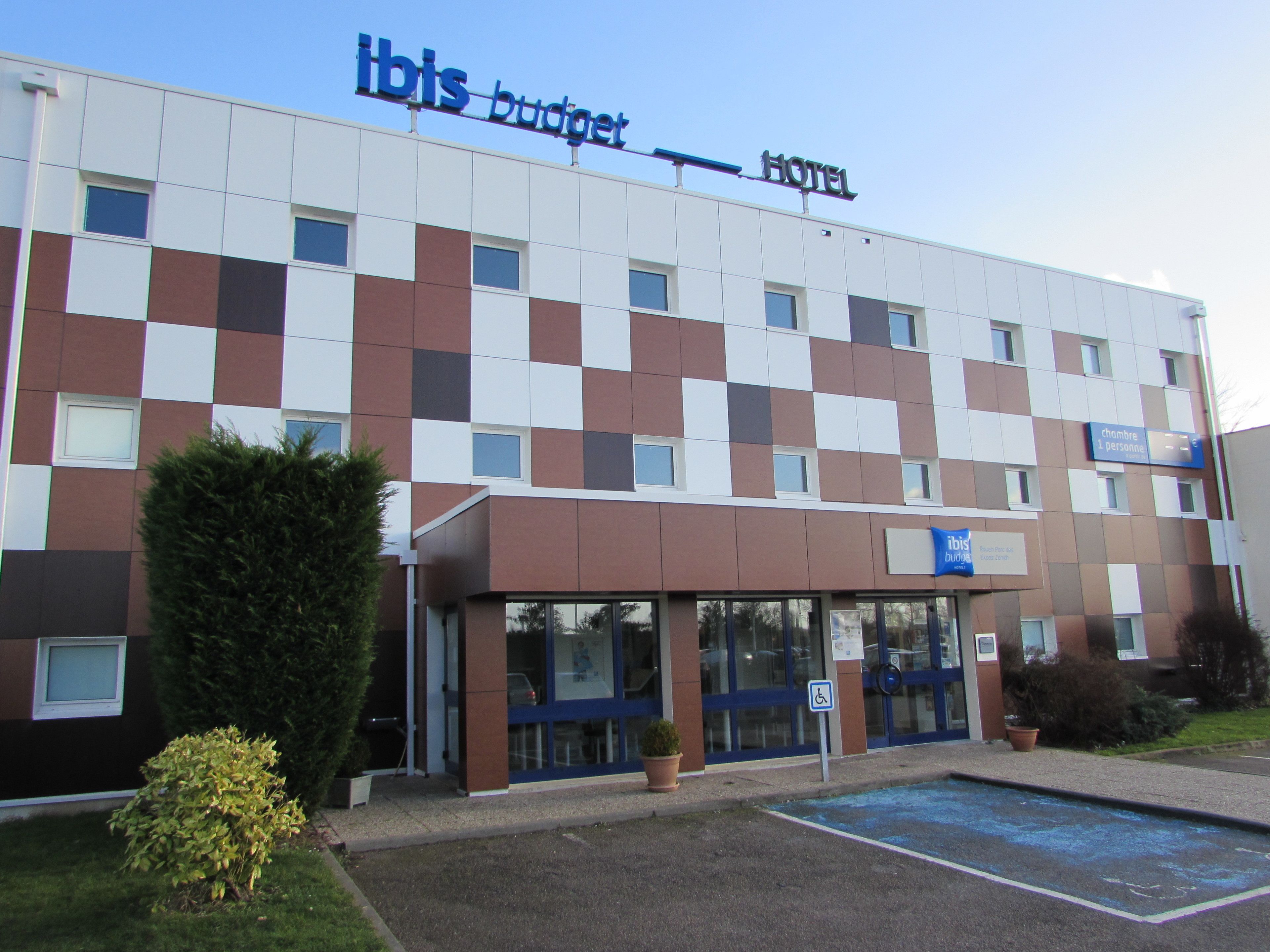 A hotel with a checkered facade, a sign indicating a single room, and a handicap parking sign.