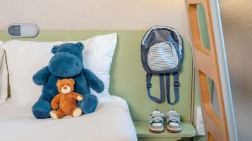 Una cama con un oso de peluche, una mochila a rayas y un par de zapatos sobre una mesita de noche.