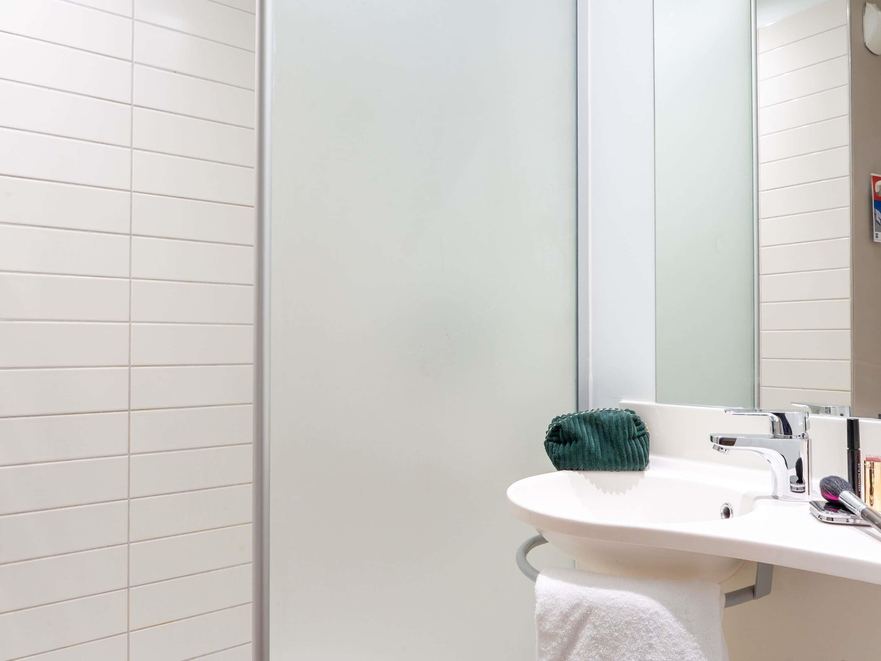 Un baño con un lavamanos blanco, un espejo y una toalla.