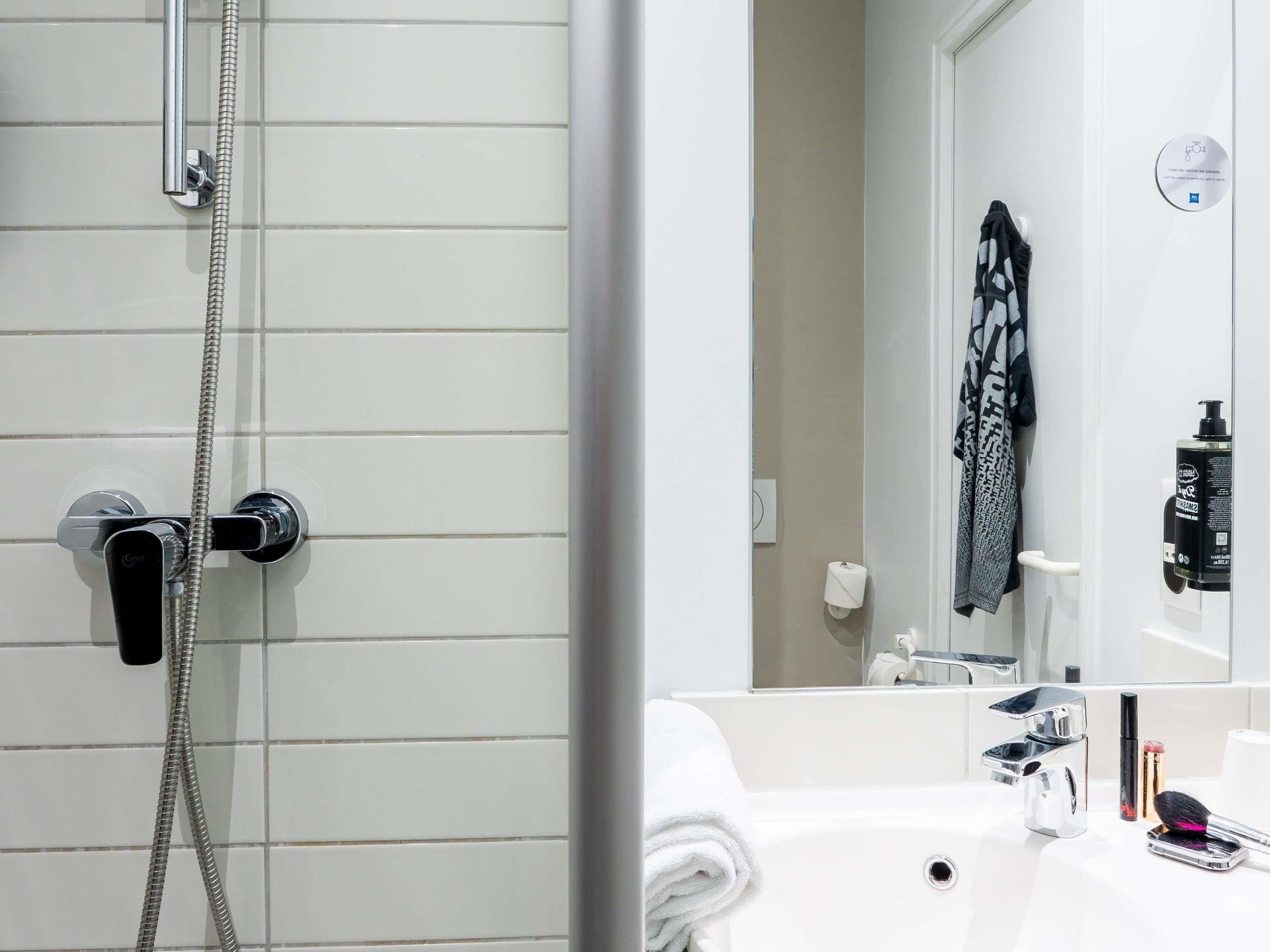 A bathroom with a shower, a sink, and a mirror.