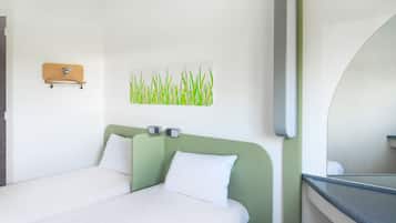 A hotel room with a bed, a wall-mounted mirror, and a picture of grass.