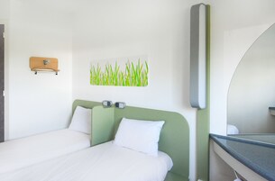 Habitación de hotel con una cama, un espejo en la pared y una imagen de césped.