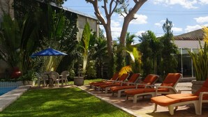 A poolside area with lounge chairs and a table under a blue umbrella. - Las Dalias Inn (Mérida)