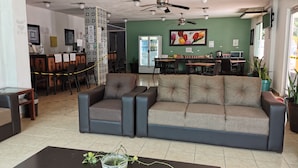 A modern interior with a sofa, a coffee table, and a dining area with chairs and tables. - Las Dalias Inn (Mérida)