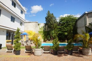 Una piscina al aire libre, sillones reclinables de piscina