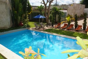 Una piscina al aire libre, sillones reclinables de piscina