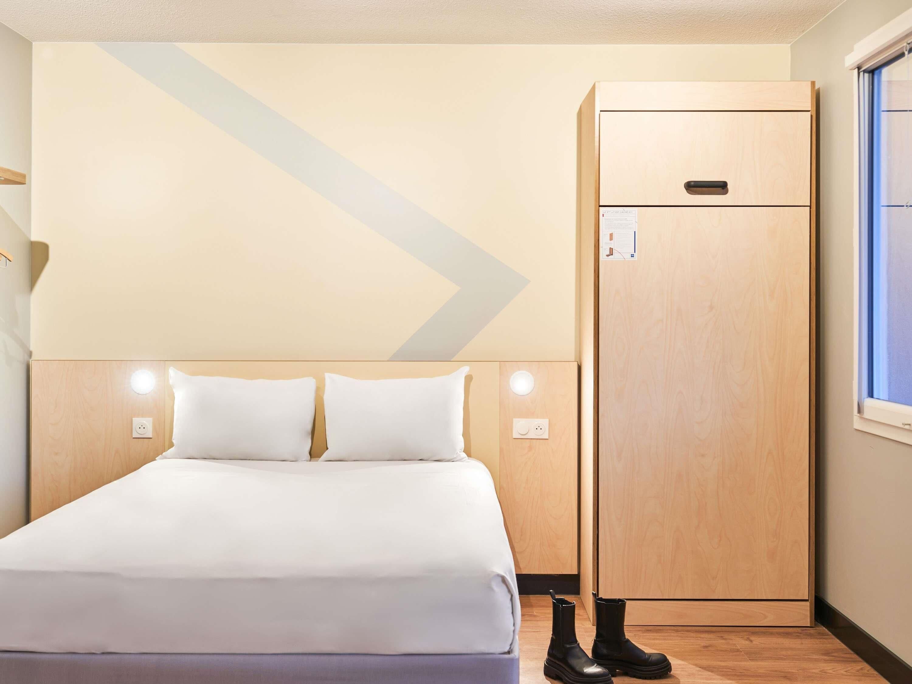 Een hotelkamer met een bed, een kledingkast en een raam.