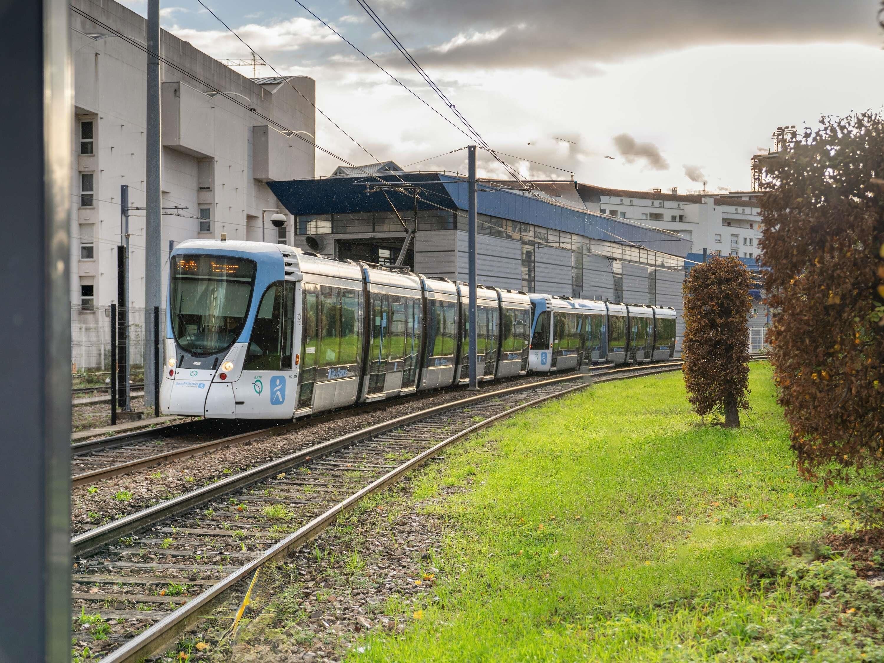 Ein Zug fährt auf Gleisen, im Hintergrund ein Gebäude.