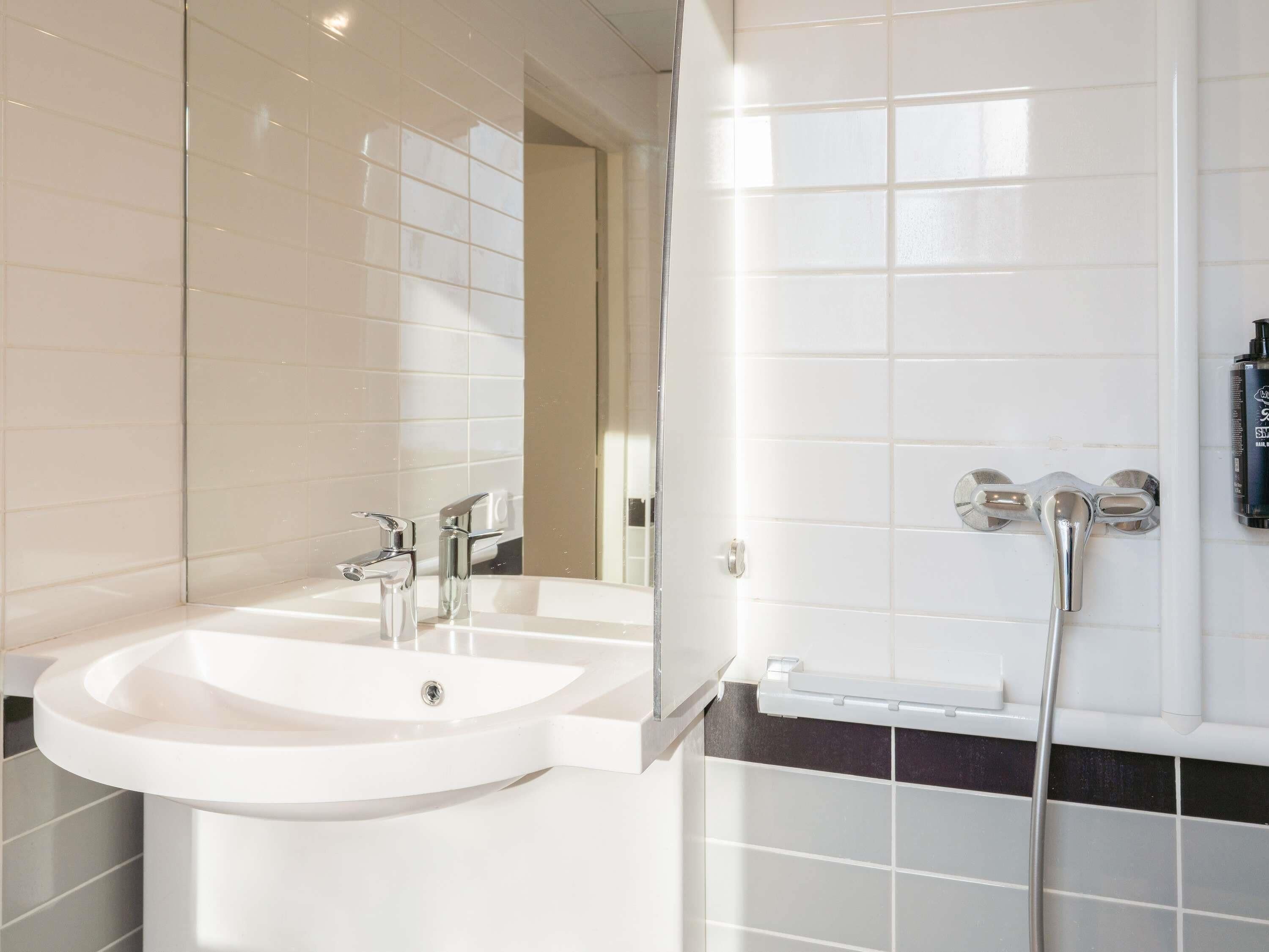 Een badkamer met twee wastafels, een spiegel en een douche.