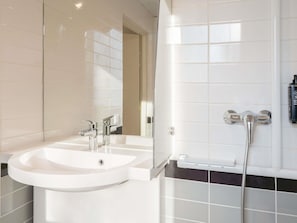 A bathroom with two sinks, a mirror, and a shower.