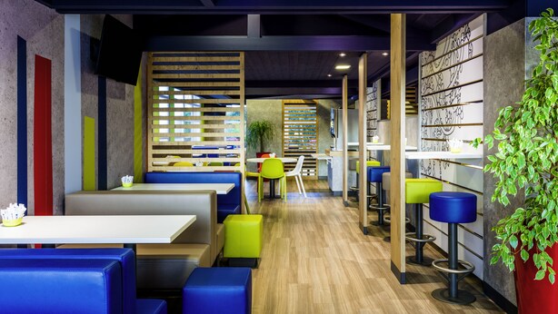 Een modern restaurantinterieur met zitjes, hoge tafels en barstoelen.