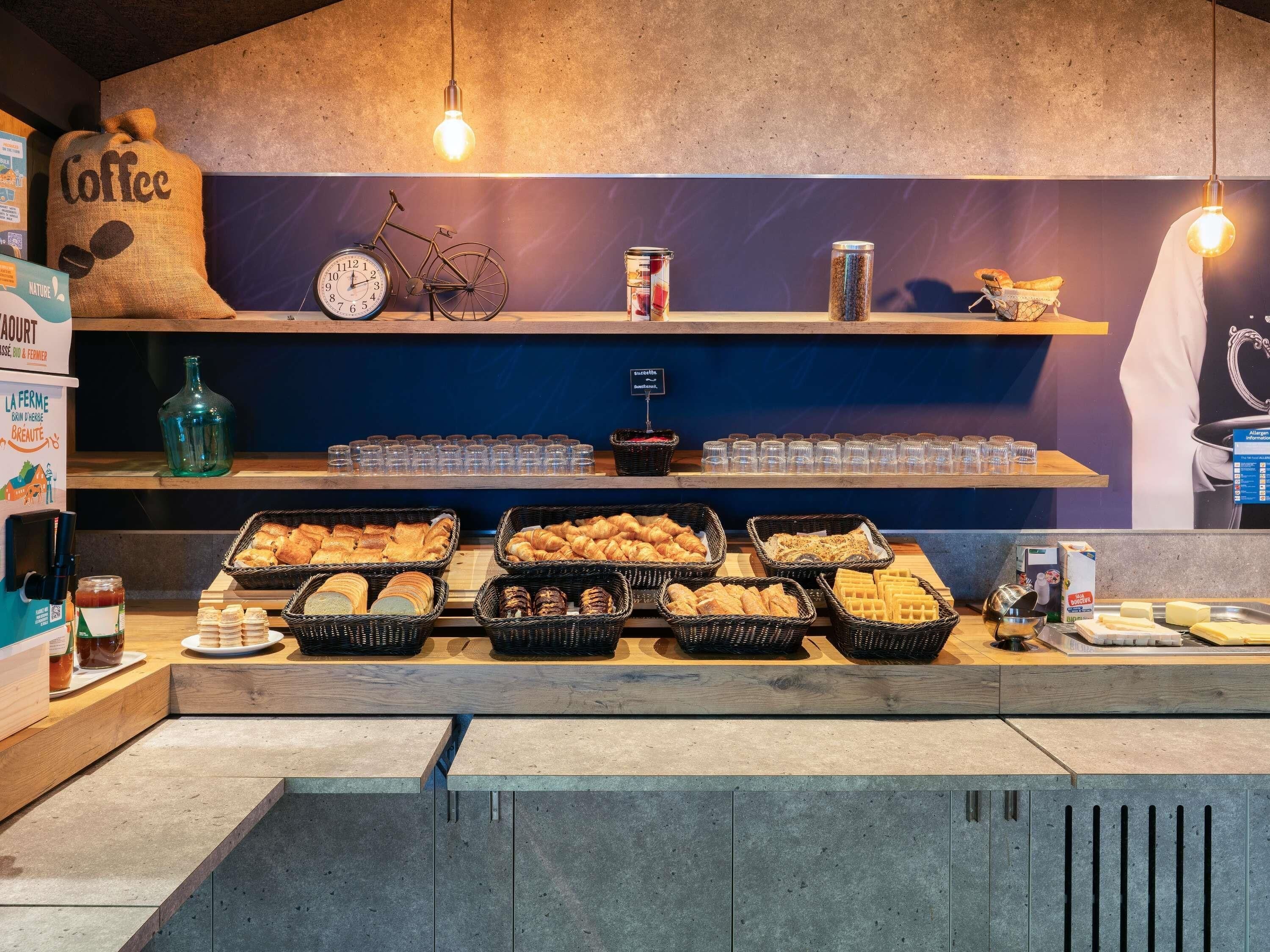 A breakfast buffet with various breads, pastries, and condiments.