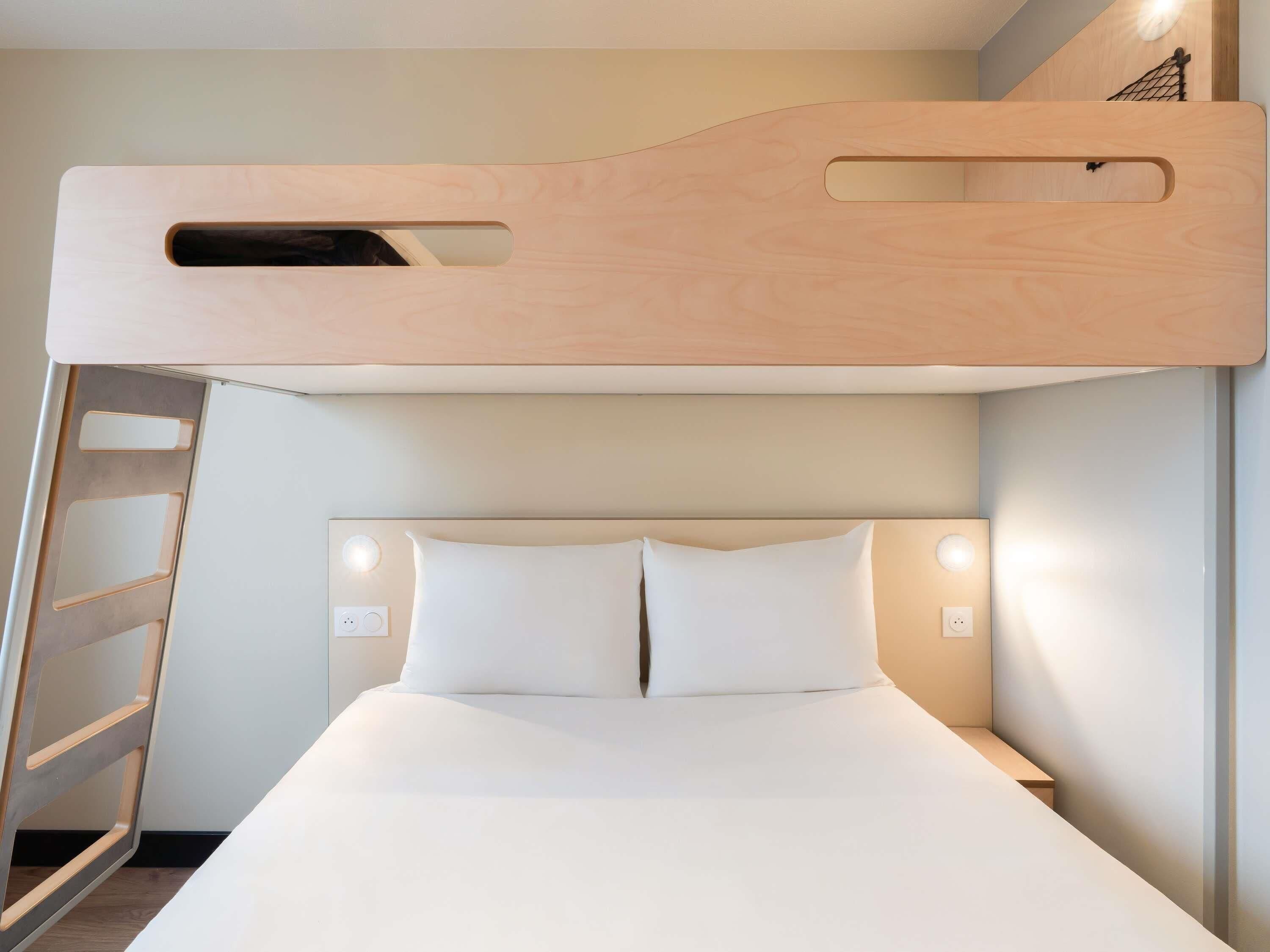 A bunk bed with a wooden headboard, a ladder, and two bedside lamps.