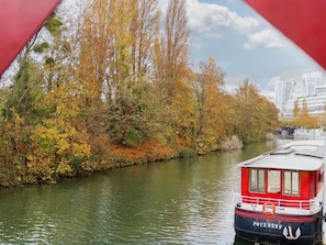 A river with autumn foliage and a red boat docked on the right.