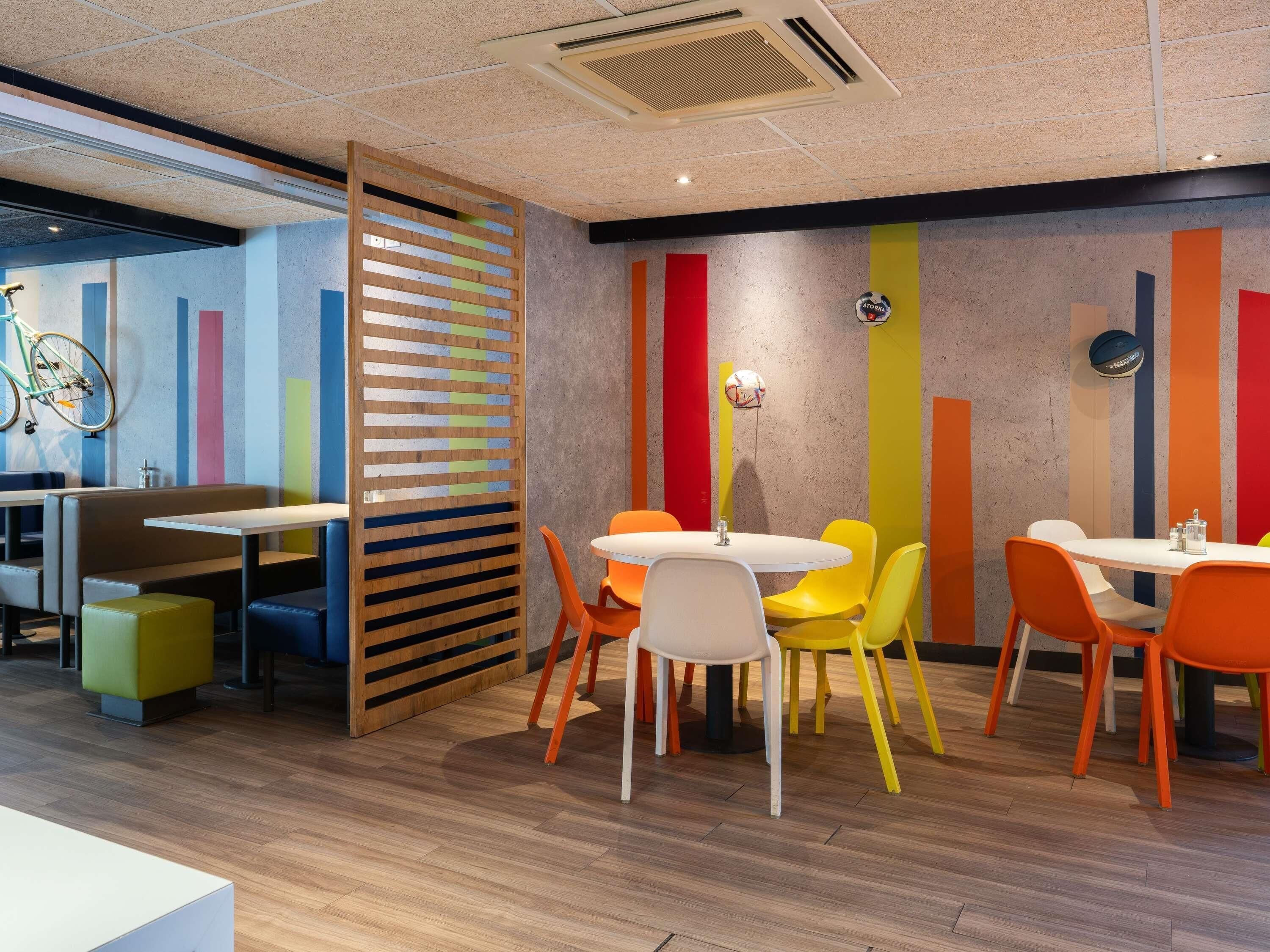 A modern interior with a wooden partition, colorful vertical stripes on the wall, and a bicycle in the background.